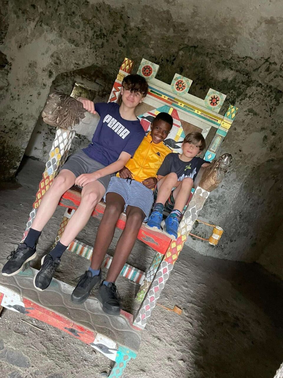 Three young people sitting on a throne.