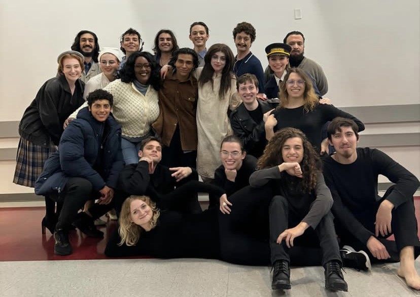 A big group of young people smiling for a photo. One person is lying down in the front of the group.