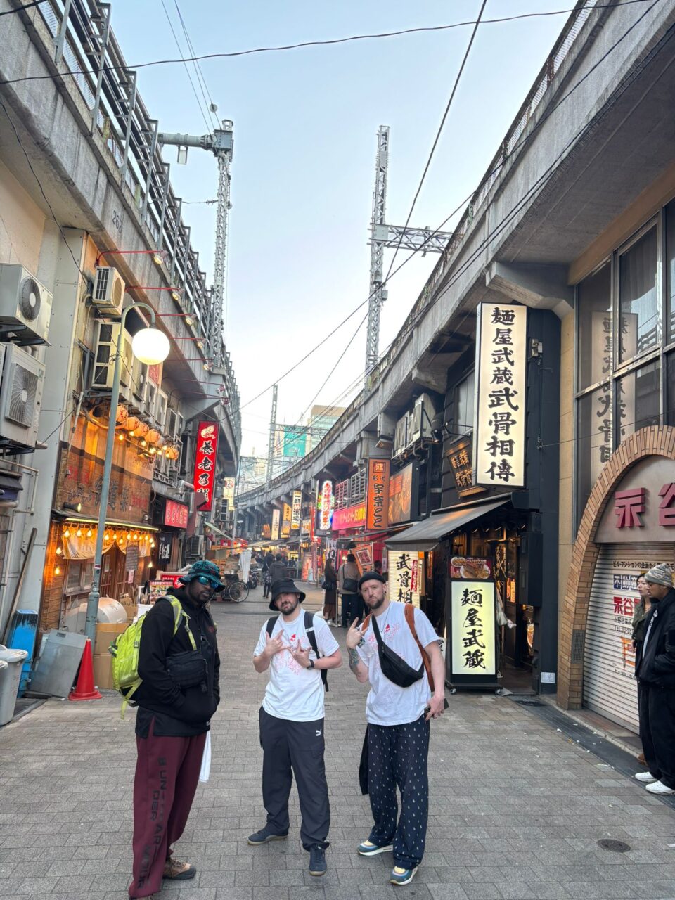 Three young men from Avant Cymru standing on a street in Tokyo posing for a photo