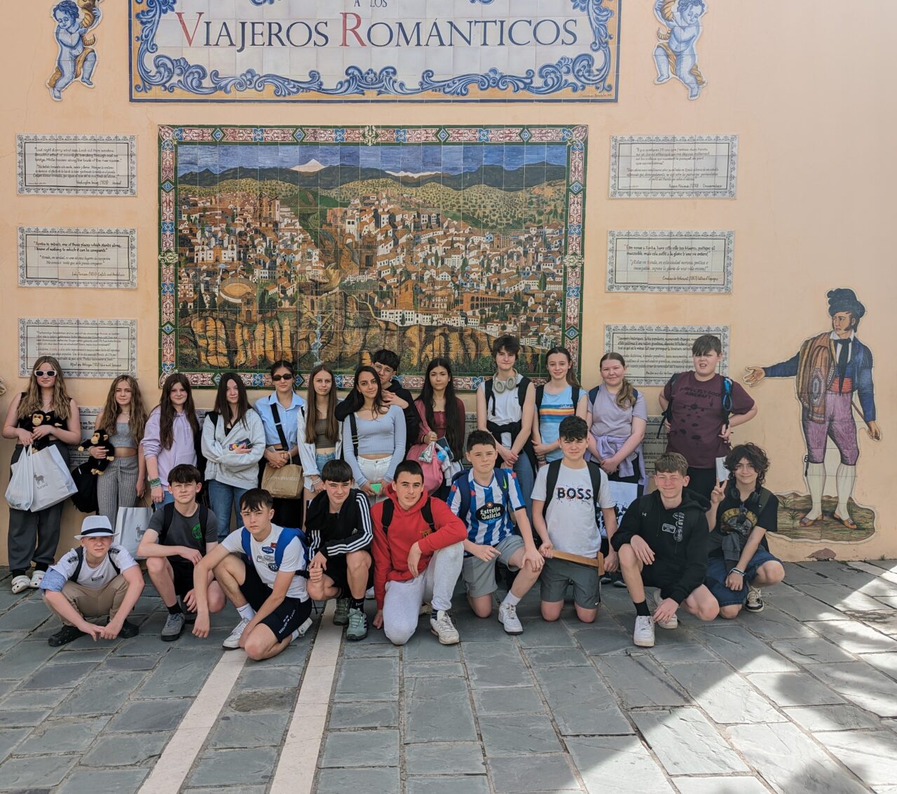 A group of Spanish and Welsh pupils stood together outside in front of a mural