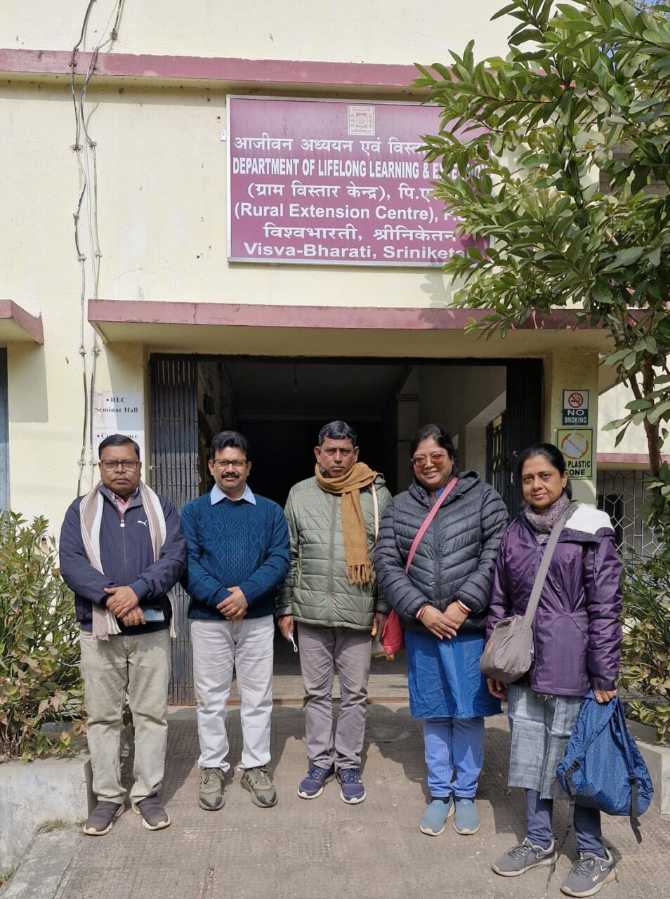 Five people stand outside the Department of Lifelong Learning and Extension at Visva-Bharati University.