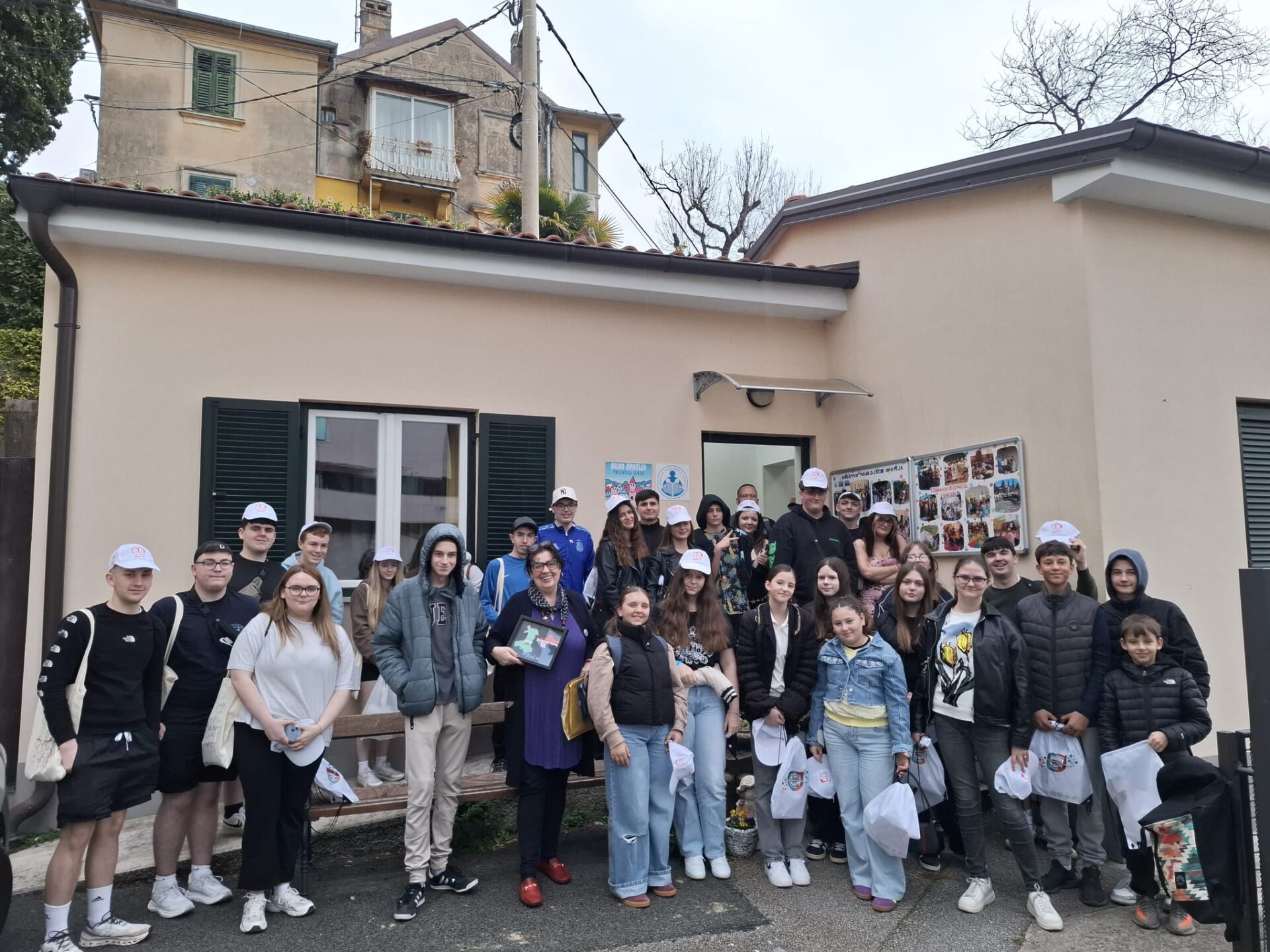Group of young people from Llais Ni and project leaders gathered outside a community building during an international exchange visit to Croatia.