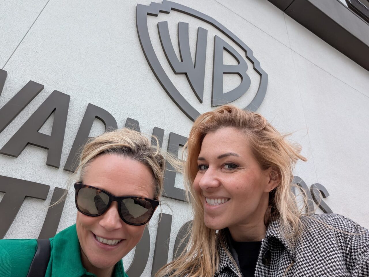 Marlen Komorowski and Sara Pepper stand in front of the Warner Bros. Studios logo.